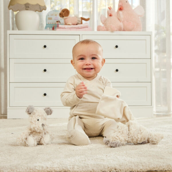 Baby in a white room with toys and a dresser