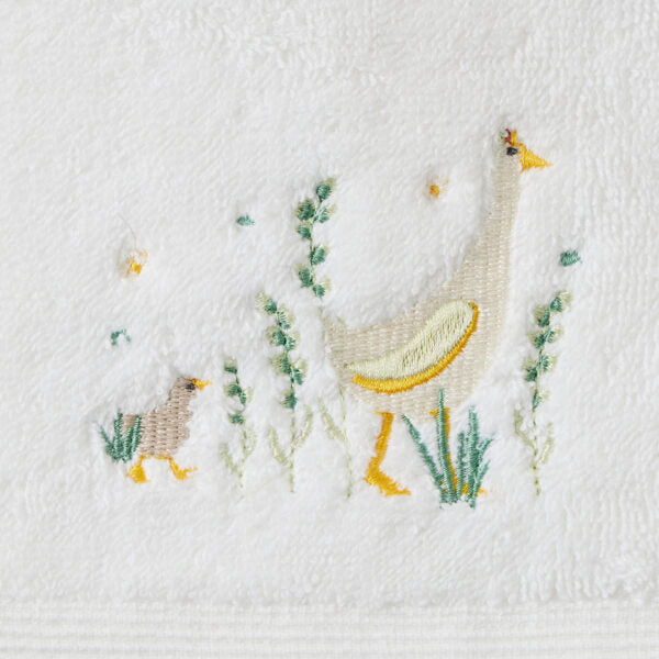 Embroidered design of a goose and duckling on a white fabric background