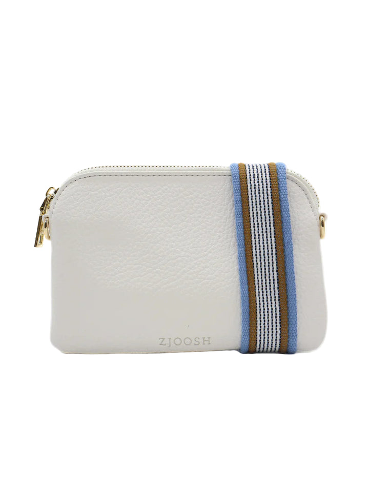 A white Missy Hugo crossbody bag with blue and brown stripes, featuring a zipper closure and a detachable wristlet.